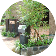 玄関ポーチを演出した自然石の植栽スペースとレンガ枕木乱形石を組み合わせたアプローチ